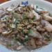 Close-up of a Cambodian-style dish featuring halved straw mushrooms sautéed with minced pork, garlic, and chopped scallions in a light savory broth, served in a ceramic bowl.