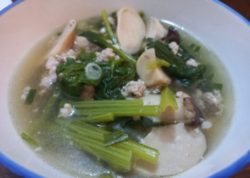 Bowl of Cambodian clear soup with sliced king oyster mushrooms, choi sum greens, ground pork, and scallions in light broth