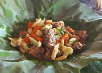 Cambodian chicken and mixed vegetables served on a fresh green lotus leaf at a rural eatery near Kampong Thom.
