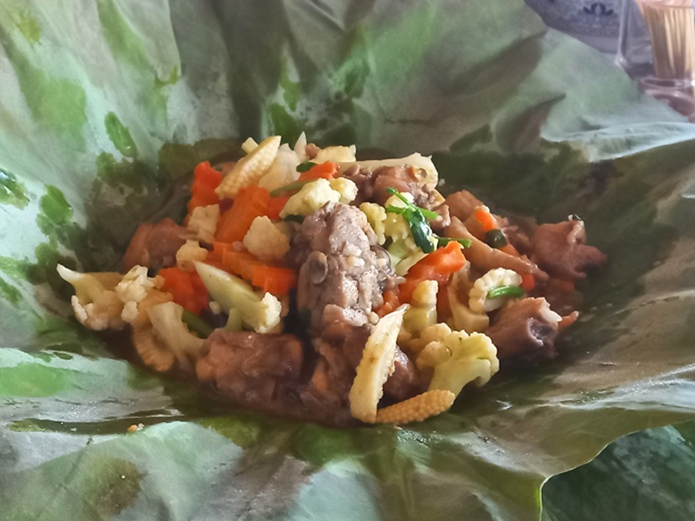 Cambodian chicken and mixed vegetables served on a fresh green lotus leaf at a rural eatery near Kampong Thom.