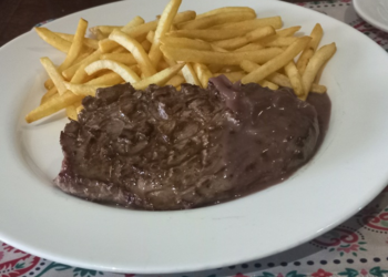 Bavette steak with red wine sauce and crispy French fries on a white plate at O’Fun restaurant in Phnom Penh, Cambodia.