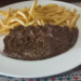 Bavette steak with red wine sauce and crispy French fries on a white plate at O’Fun restaurant in Phnom Penh, Cambodia.
