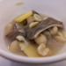 Close-up of Cantonese pickled vegetable pig stomach soup with ginger slices, lotus seeds, and tender offal pieces in a white bowl at Fisherman Quay Restaurant in Phnom Penh.