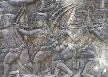 Bas-relief at Bayon temple showing Khmer archers and crossbowmen marching in formation, carved in sandstone with detailed clothing and weaponry.