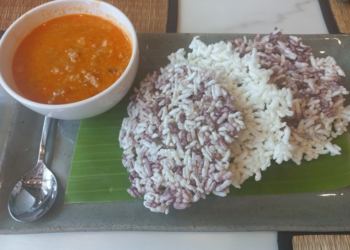Crispy purple-and-white Cambodian rice crackers served on banana leaf with a bowl of orange coconut curry dipping sauce at Kraya Angkor restaurant in Phnom Penh.