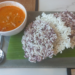 Crispy purple-and-white Cambodian rice crackers served on banana leaf with a bowl of orange coconut curry dipping sauce at Kraya Angkor restaurant in Phnom Penh.