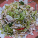 Plate of finely sliced Cambodian bitter melon salad mixed with shrimps, beansprouts, lemongrass, fresh herbs, and chili on a floral dish