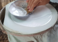 Woman spreading rice batter on steamer for traditional Cambodian rice paper production in Battambang