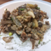 A plate of white rice topped with Cambodian stir-fried eggplant, mushrooms and minced pork.