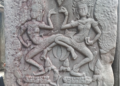 Dancing apsaras bas-relief at Bayon temple in Angkor Thom, showing two elaborately adorned celestial dancers carved in weathered sandstone.