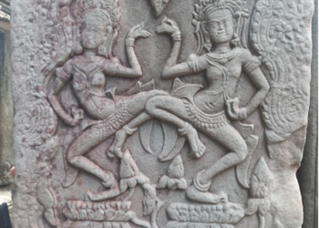 Dancing apsaras bas-relief at Bayon temple in Angkor Thom, showing two elaborately adorned celestial dancers carved in weathered sandstone.