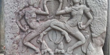 Dancing apsaras bas-relief at Bayon temple in Angkor Thom, showing two elaborately adorned celestial dancers carved in weathered sandstone.