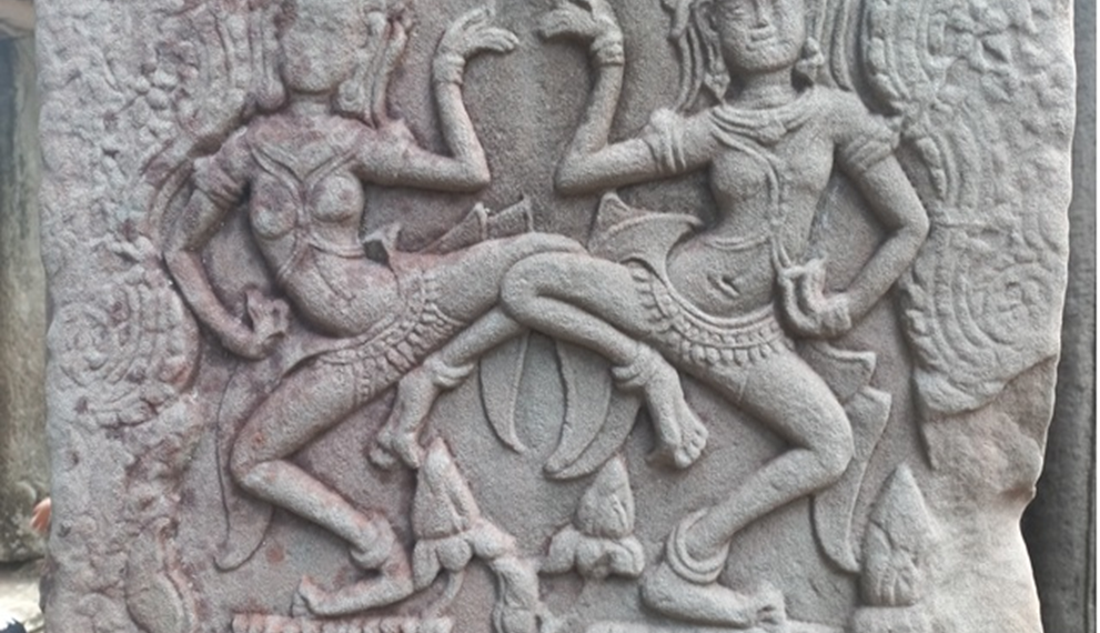 Dancing apsaras bas-relief at Bayon temple in Angkor Thom, showing two elaborately adorned celestial dancers carved in weathered sandstone.
