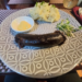 House-made blood sausage with mashed potatoes, mustard sauce, and greens served on a patterned plate at La Ferme de Bassac restaurant in Siem Reap.