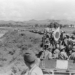 Japanese Imperial Army troops and supply wagons advancing along a dirt road through rural Indochina in 1940, with mountains visible in the background
