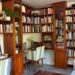 Cozy corner of the Angkor Database Documentation Center with floor‑to‑ceiling wooden bookshelves, a striped chair, and a reading desk filled with books and maps.