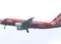 Avion de la compagnie AirAsia peint en rouge avec la mention Cambodia sur le fuselage, volant dans le ciel avant l’atterrissage