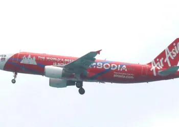 Avion de la compagnie AirAsia peint en rouge avec la mention Cambodia sur le fuselage, volant dans le ciel avant l’atterrissage