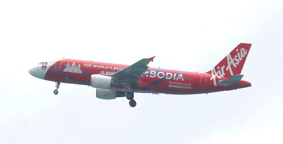 Avion de la compagnie AirAsia peint en rouge avec la mention Cambodia sur le fuselage, volant dans le ciel avant l’atterrissage