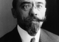 Black‑and‑white studio portrait of Albert Sarraut in 1914, shown from the chest up in a dark suit, white shirt and patterned tie, facing the camera against a plain, dark background.