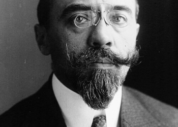 Black‑and‑white studio portrait of Albert Sarraut in 1914, shown from the chest up in a dark suit, white shirt and patterned tie, facing the camera against a plain, dark background.
