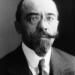 Black‑and‑white studio portrait of Albert Sarraut in 1914, shown from the chest up in a dark suit, white shirt and patterned tie, facing the camera against a plain, dark background.