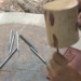 Close-up of a Siem Reap artisan using metal chisels and a wooden mallet on a leather panel to create traditional sbaek thom Khmer shadow puppets.
