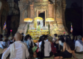 De nuit, au temple de Lolei dans la province de Siem Reap, un groupe de fidèles assis sur des nattes fait face à un ancien sanctuaire en briques illuminé, décoré de parasols jaunes, de fleurs et d’offrandes, en attendant le moment précis fixé par la position de la lune pour lancer une cérémonie de la Fête de l’Eau.