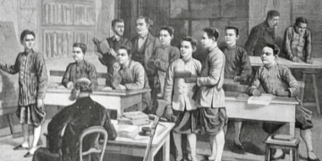 Black and white illustration of a classroom at the École cambodgienne in Paris, showing Cambodian male students in traditional garments standing and sitting at wooden desks while two European teachers supervise the lesson from the front and back of the room.