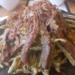 Close-up of Cambodian morning glory salad at Kraya Angkor Restaurant in Phnom Penh, featuring crispy battered morning glory topped with sliced grilled beef and golden fried shallots on a dark plate.