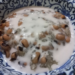 Close-up of a Cambodian dessert with black-eyed peas and sticky rice covered in creamy coconut milk, served in a blue-and-white patterned ceramic bowl.