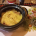 Close-up of tarticlette at La Guinguette de Siem Reap, a French-style potato, bacon, onion and raclette cheese gratin served in a black dish with green salad on the side in Siem Reap, Cambodia.