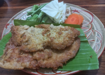 Cambodian omelette made with trei proma salted semi-dried fish, served on banana leaf with cabbage, long beans, okra, eggplant and carrot on a patterned plate.