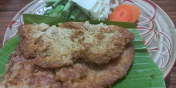 Cambodian omelette made with trei proma salted semi-dried fish, served on banana leaf with cabbage, long beans, okra, eggplant and carrot on a patterned plate.