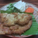 Cambodian omelette made with trei proma salted semi-dried fish, served on banana leaf with cabbage, long beans, okra, eggplant and carrot on a patterned plate.
