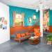 Reconstitution d’un salon cambodgien des années du Sangkum avec canapé et fauteuil orange, télévision vintage et décor mural coloré au Musée SOSORO