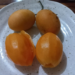 Four ripe marian plums, two peeled and two whole, on a speckled ceramic plate on a wooden table, illustrating Cambodian home-style fruit enjoyment.