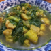 Close up of a bowl of samla prahae, traditional Cambodian vegetable meat soup with pumpkin, leafy greens and fermented fish in a clear lemongrass broth.
