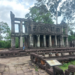Two storied stone pavilion with round columns at Preah Khan temple in Angkor, surrounded by lush trees and ancient terraces, Siem Reap, Cambodia.