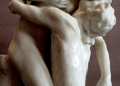 Marble sculpture Shakuntala by Camille Claudel showing two nude lovers locked in a tender embrace, inspired by Kalidasa’s Sanskrit play, against a neutral museum background.