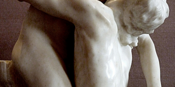 Marble sculpture Shakuntala by Camille Claudel showing two nude lovers locked in a tender embrace, inspired by Kalidasa’s Sanskrit play, against a neutral museum background.