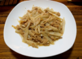 Cambodian stir-fried lotus stem with ground pork on a white plate over a wooden table