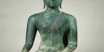 Fourteenth century Sukhothai bronze Buddha statue seated cross-legged in meditation, right hand resting on knee, left hand in lap, with flame-like finial on top of the head.