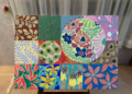 Acrylic painting by Cambodian artist Tith Veasna showing a grid of colorful orchid-inspired panels surrounding a large circular floral motif, blending abstract patterns with botanical forms in a soft-lit Phnom Penh interior.