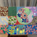 Acrylic painting by Cambodian artist Tith Veasna showing a grid of colorful orchid-inspired panels surrounding a large circular floral motif, blending abstract patterns with botanical forms in a soft-lit Phnom Penh interior.