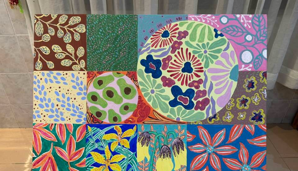 Acrylic painting by Cambodian artist Tith Veasna showing a grid of colorful orchid-inspired panels surrounding a large circular floral motif, blending abstract patterns with botanical forms in a soft-lit Phnom Penh interior.