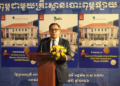 Blaise Kilian, co-directeur du musée SOSORO, prononce un discours de lancement devant un pupitre décoré de fleurs, avec en arrière-plan deux grands visuels du nouvel ouvrage illustré sur le Musée de l’Économie et de la Monnaie Preah Srey Içanavarman, en khmer, français et anglais