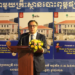 Blaise Kilian, co-directeur du musée SOSORO, prononce un discours de lancement devant un pupitre décoré de fleurs, avec en arrière-plan deux grands visuels du nouvel ouvrage illustré sur le Musée de l’Économie et de la Monnaie Preah Srey Içanavarman, en khmer, français et anglais