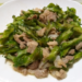 Close-up of Cambodian stir-fried winged beans with sliced pork on a white plate, glistening with light sauce and showing crisp green texture and home-style presentation.