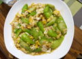 Plate of Cambodian luffa stir fried with scrambled eggs in light savory sauce on a wooden table, highlighting a simple Khmer home cooked meal.